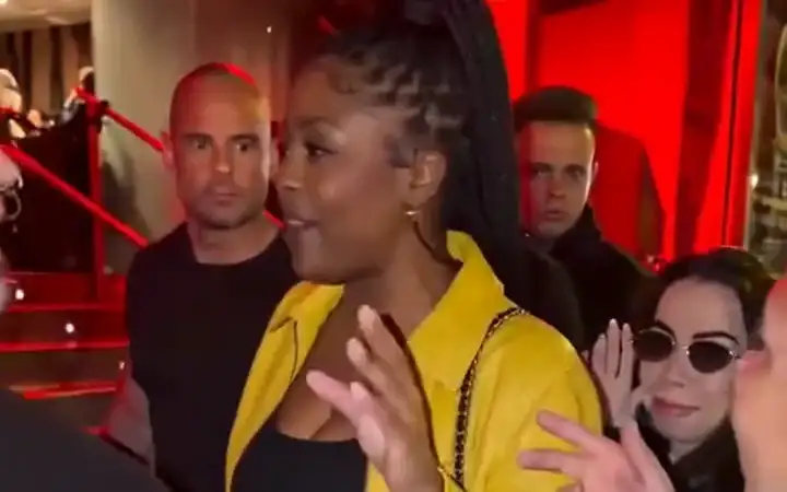 Yellow-jacket lead freestyling at a red-lit entrance with the crowd behind her
