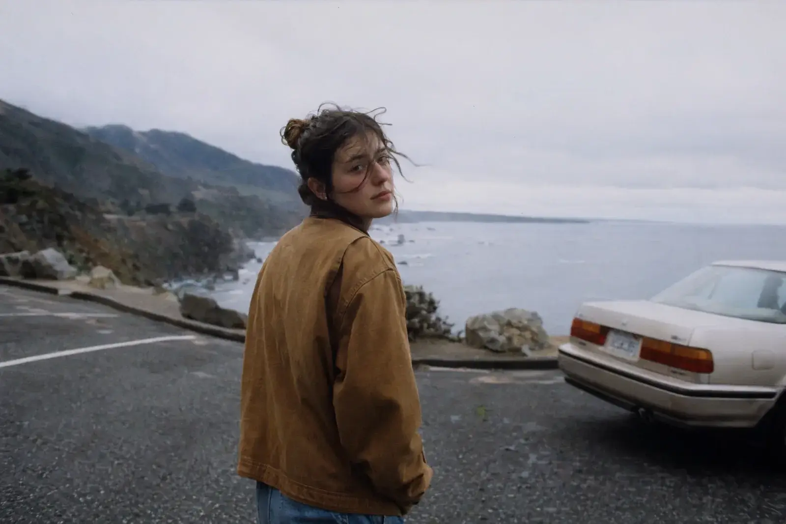 AI Image Generator example: cinematic coastal roadside portrait looking back toward the camera