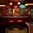 Reference to Video example: a dim bar with stools, bottles, and a pool table