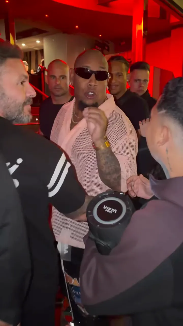 Street freestyle behind a portable speaker at a red-lit entrance